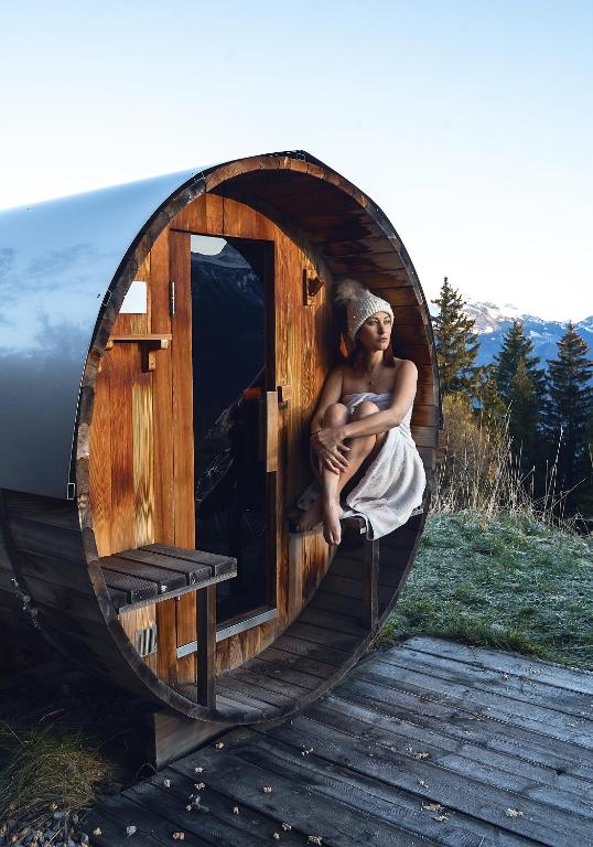 Badstue hos Whitepod Eco-Luxury Hotel, stemningsfull kveld i Alpene, dame i håndkle som nyter utsikten over alpene