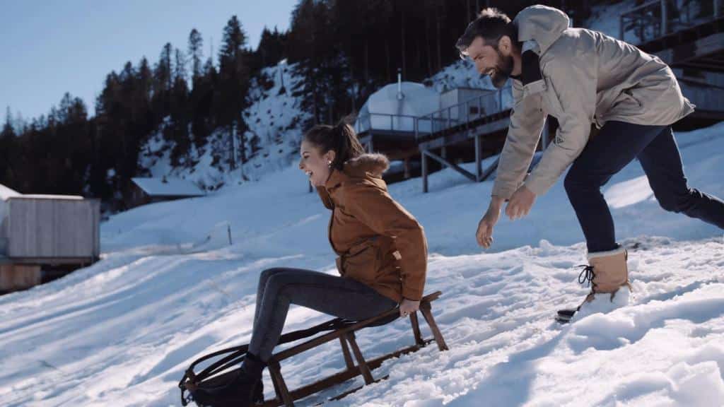 Gjester på kjelke i snøen ved Whitepod Original i Valais, Sveits