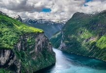 Sykkelferie i Norge – fra fjord til fjell med komfort langs veien Geirangerfjorden sett ovenfra med bratte fjellsider og dypblått vann.