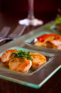 Grillet sjømat servert på tallerken i restauranten Wilde’s på The Lodge at Ashford Castle i Irland