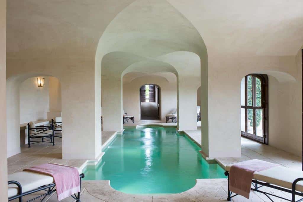 Innendørs spa-basseng på Il Borro Relais & Châteaux i Toscana med historiske hvelv, naturlig lys og en stillferdig, luksuriøs atmosfære.