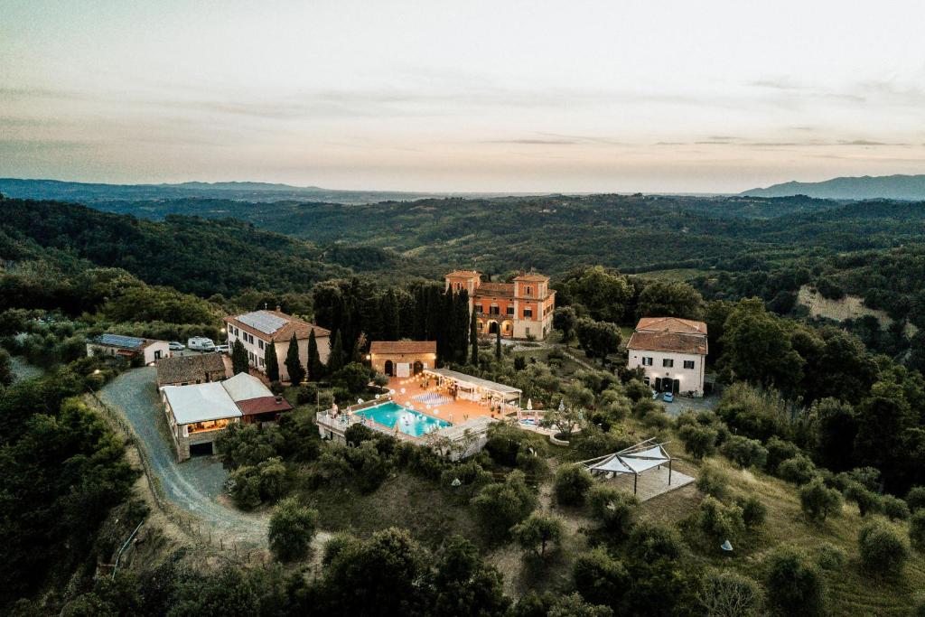 Luftfoto av Villa Lena i Toscana omgitt av skog, åser og historiske bygninger – et kunstnerisk retreat som kombinerer slow living, natur og landlig luksus.