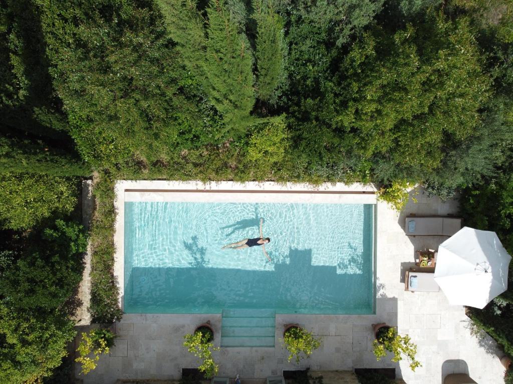 Privat basseng omgitt av frodig grønt landskap på Borgo Santo Pietro i Toscana, sett ovenfra, med rolig luksuriøs atmosfære og fokus på slow living og natur.