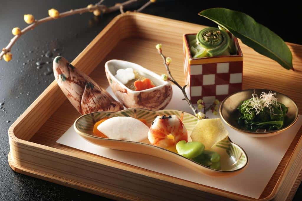 Tradisjonell kaiseki-rett servert på japansk brett med sesongbaserte ingredienser og kunstnerisk presentasjon.