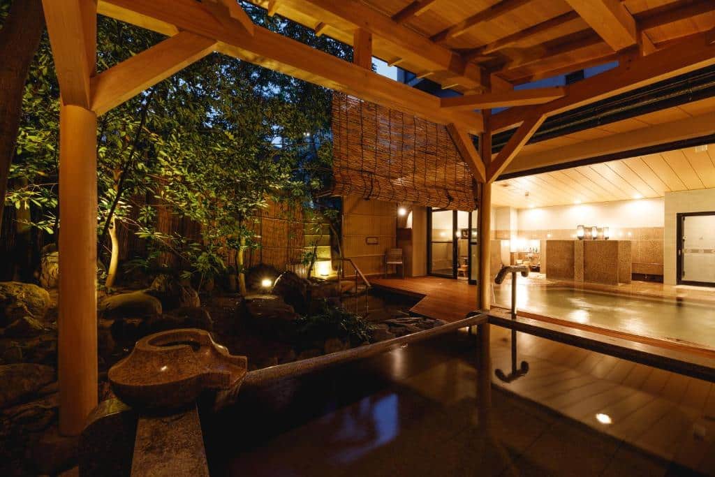 Utendørs og innendørs onsen-bad ved Tachibana Shikitei i Japan, med tradisjonell japansk arkitektur, varme kilder og stemningsfull belysning i rolige hageomgivelser.