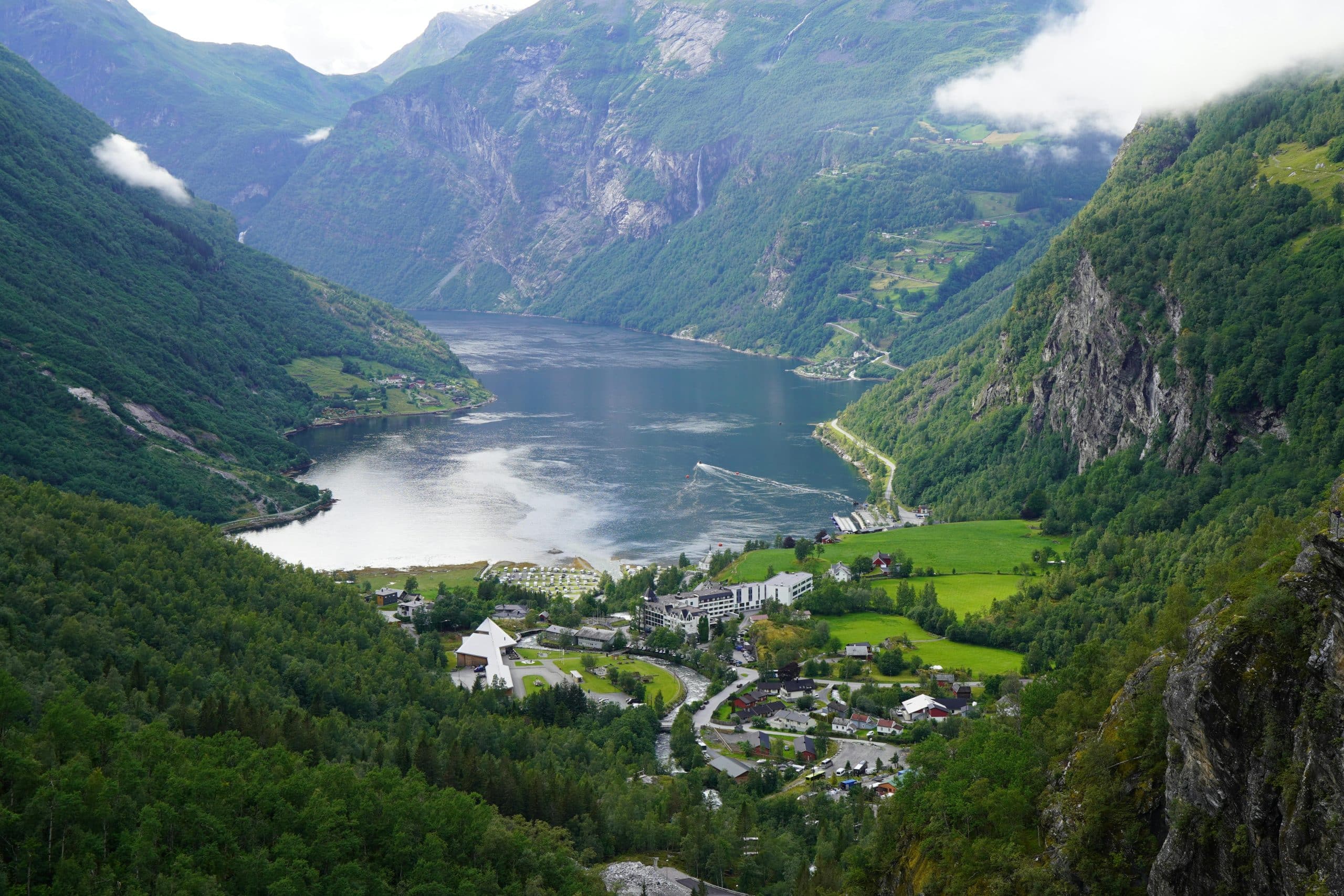 Utsikt over Geirangerfjord og bygda Geiranger omgitt av bratte fjell og grønn natur i Norge.